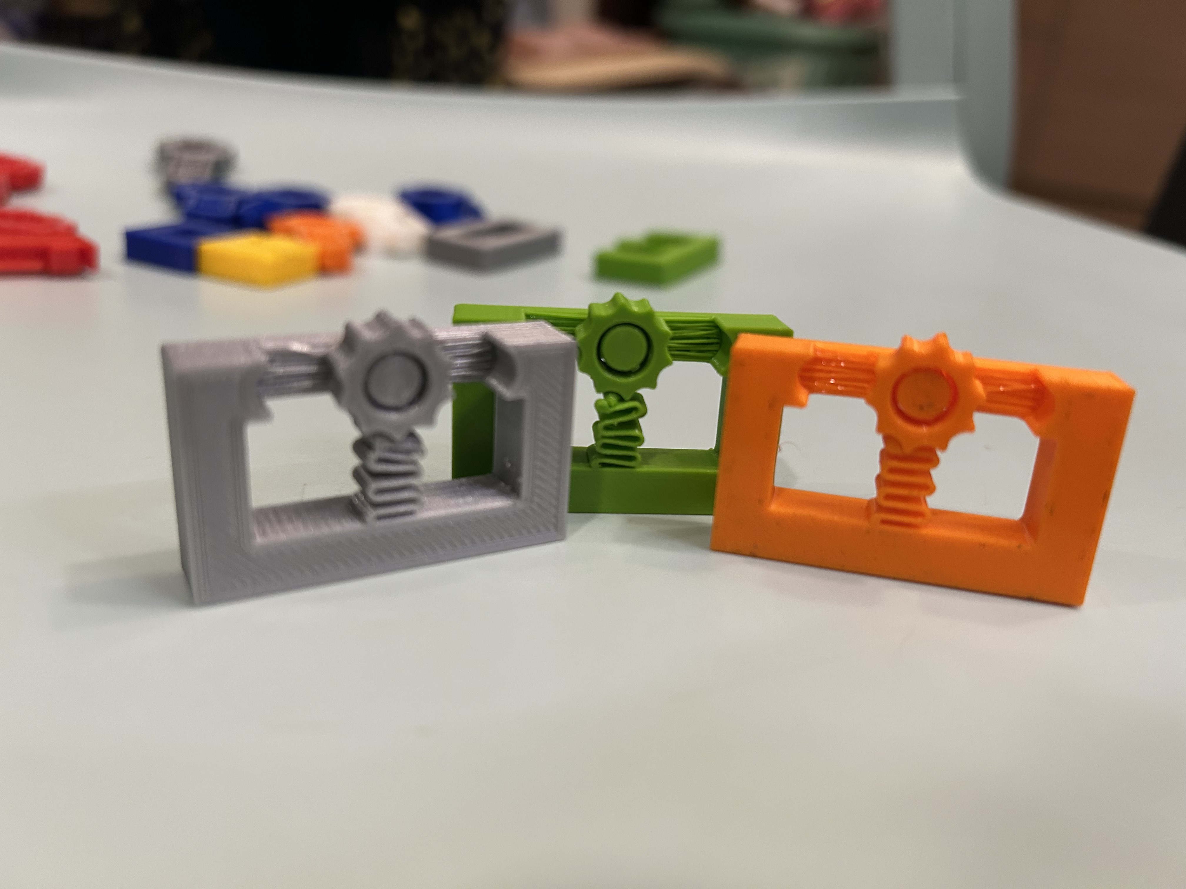 Three gear-and-spring prototypes, including Version 4 with larger gear teeth