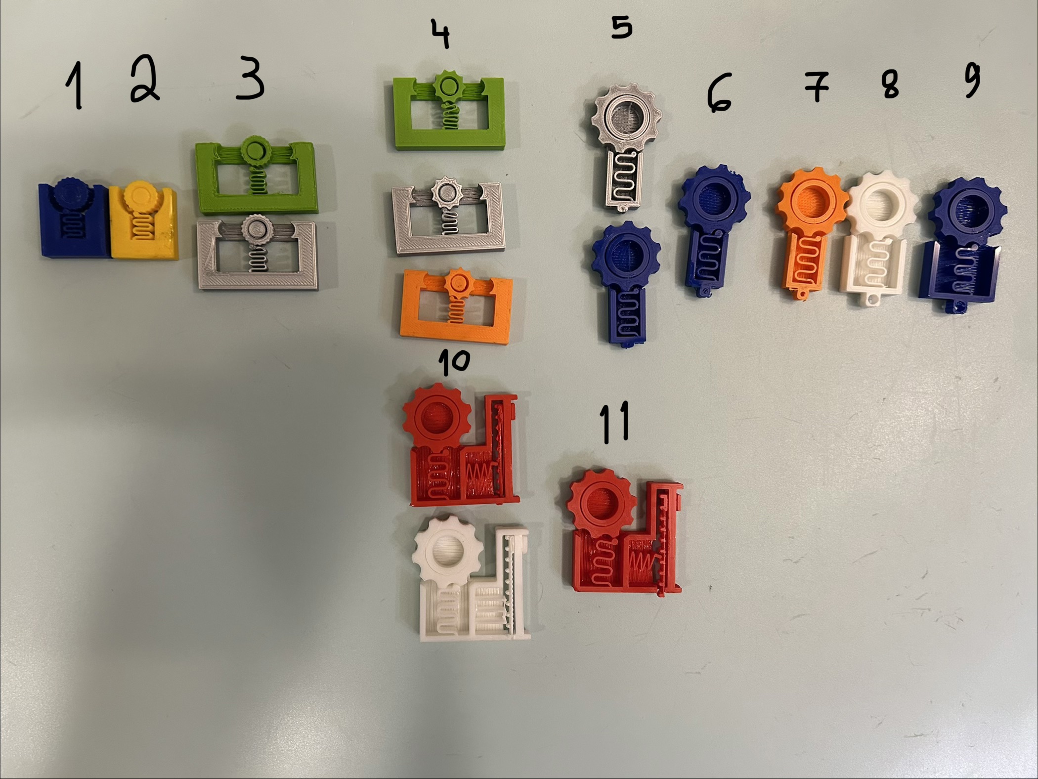 Numbered prototypes arranged in order, from the first gear mechanisms to the final gear-and-slider toy